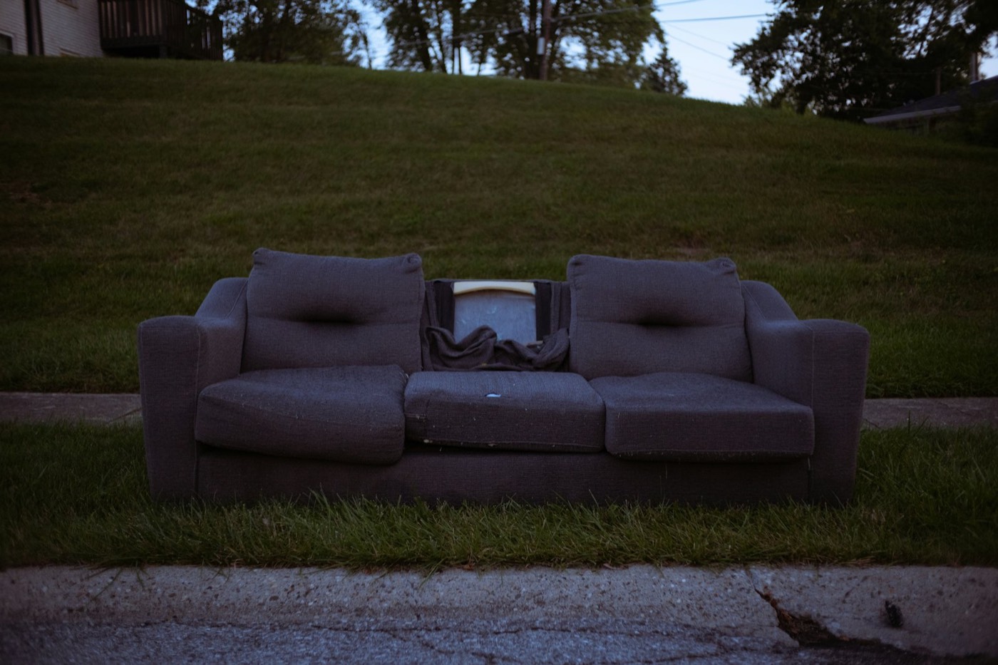 Old gray couch left out by the curb