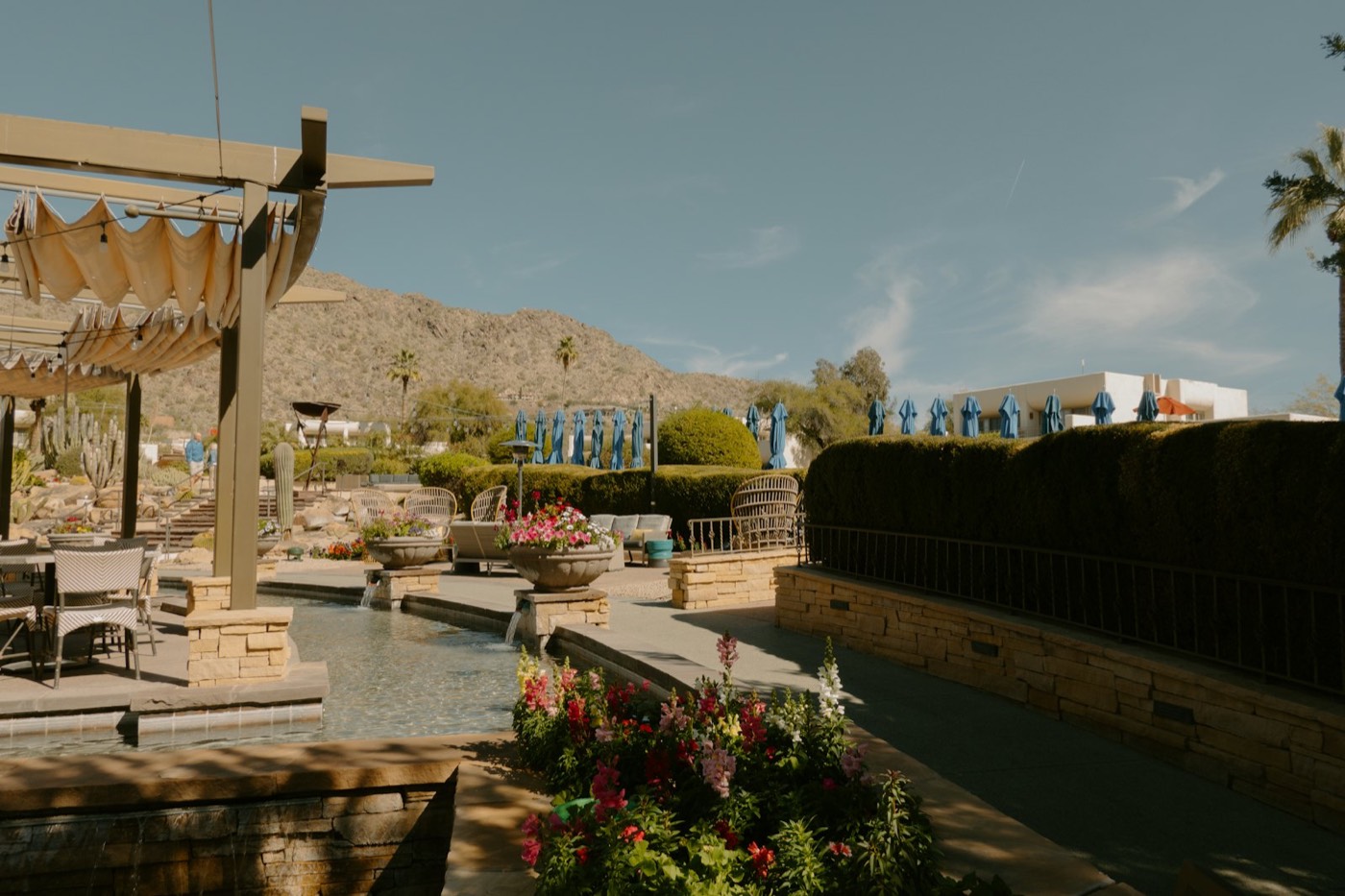 Desert patio with shade sails, a water feature, and mountain views